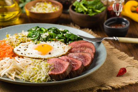 Korean beef with sprouts, spinach and fried egg. Front view.の写真素材