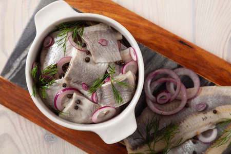 Herring fillets in oil. Served with onion in a bowl. Wooden background.の写真素材