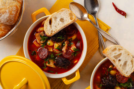 Traditional Spanish goulash soup. Fabada Asturiana. Served with a yellow clay pot with lid. Top view.の写真素材