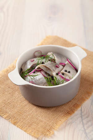 Herring fillets in oil. Served with onion in a bowl. Wooden background.の写真素材
