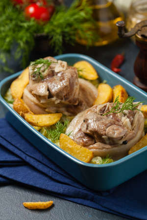 Boiled knuckle, served with cabbage and baked potatoes. Front view. Darkblue background. Dark mod.の写真素材