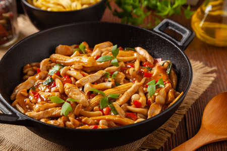 Traditional noodles with shimeji mushrooms and chicken. Prepared in a wok. Wooden background.の写真素材