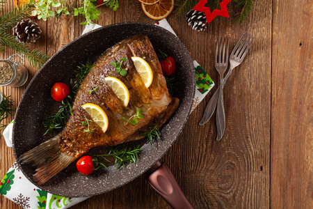 Fried carp whole. Served with lemon and cherry tomatoes. Served in a pan for frying fish.の写真素材