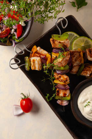 Grilled skewers with chicken, pepper, and onion. Served with sauce. Painted, bright background.の写真素材