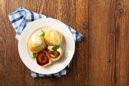Dumplings with plums, topped with plum sauce or served with cream and sugar. Top view.の写真素材