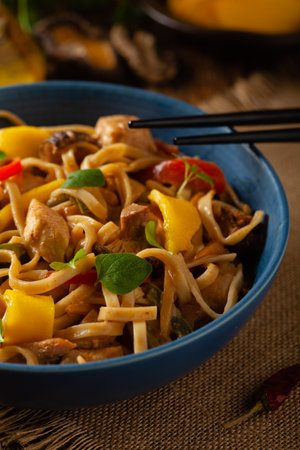 Fried chicken with mango and coconut milk with noodles. Prepared in a wok. Front view. Served in a blue bowl.の写真素材