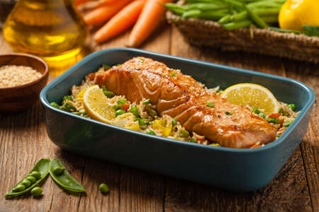 Asian dish. Fried salmon with rice and vegetables. Sprinkled with sesame seeds. Front view. Natural background.の写真素材