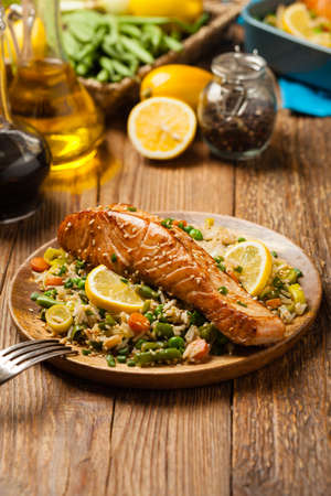 Asian dish. Fried salmon with rice and vegetables. Sprinkled with sesame seeds. Front view. Natural background.の写真素材