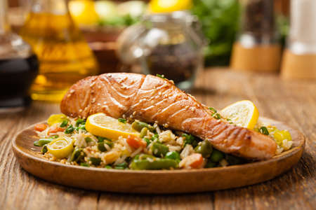 Asian dish. Fried salmon with rice and vegetables. Sprinkled with sesame seeds. Front view. Natural background.の写真素材