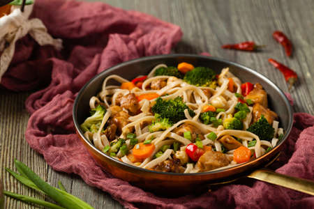 stir-fry pasta with chicken, broccoli and carrots. Served in a frying pan.の写真素材