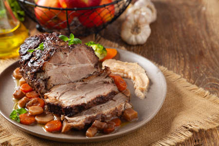 Whole roasted pork neck, stewed in wine with vegetables. Served with applesauce. Traditional Swiss dish.の写真素材