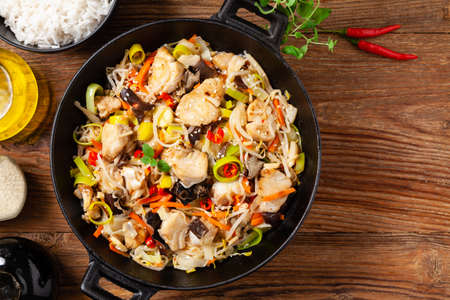 Chinese style cod, prepared in a wok. Natural wooden background.の写真素材