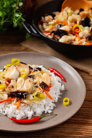 Chinese style cod, served on a plate with white rice. Natural wooden background.の写真素材