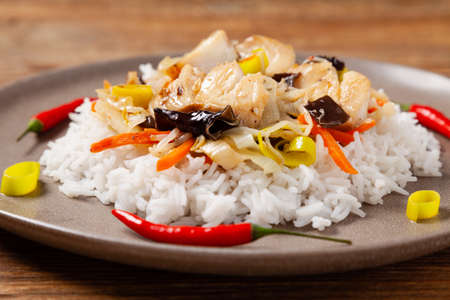 Chinese style cod, served on a plate with white rice. Natural wooden background.の写真素材
