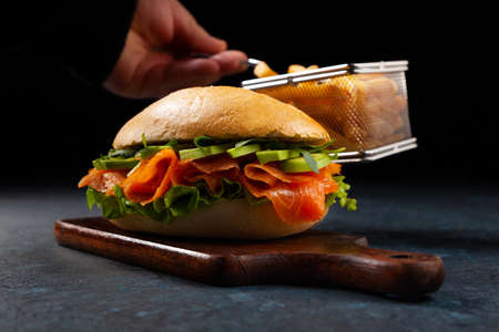 Salmon sandwich. A large roll. Dark mood. Black background.の写真素材