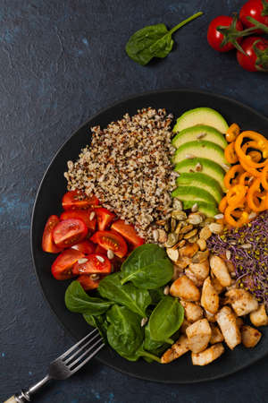 Salad with quinoa, avocado and chicken. Top view. Served on a black plate.の写真素材