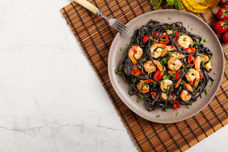 Black pasta with roasted prawns. Served on a plate. Stone background. Chopsticks or fork.の写真素材