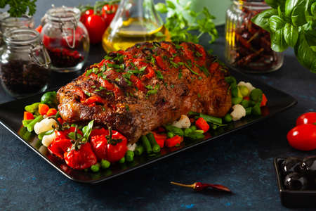 Whole roasted, stuffed with tomatoes and olives, pork neck. Dark background, dark mood.の写真素材