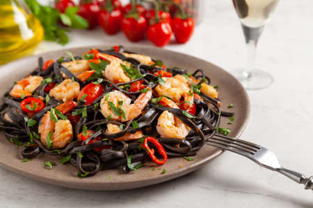Black pasta with roasted prawns. Served on a plate. Stone background. Chopsticks or fork.の写真素材