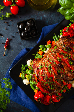Whole roasted, stuffed with tomatoes and olives, pork neck. Dark background, dark mood.の写真素材
