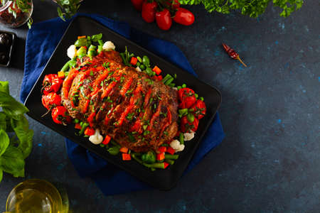 Whole roasted, stuffed with tomatoes and olives, pork neck. Dark background, dark mood.の写真素材
