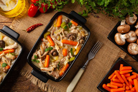 Traditional chicken stew with mushrooms and vegetables. Chicken casserole. Served in black pots.の写真素材