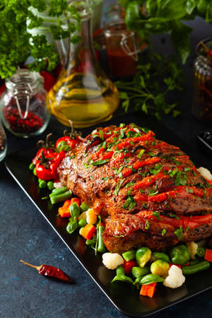 Whole roasted, stuffed with tomatoes and olives, pork neck. Dark background, dark mood.の写真素材