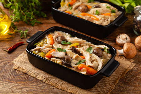 Traditional chicken stew with mushrooms and vegetables. Chicken casserole. Served in black pots.の写真素材