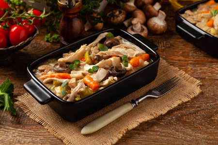 Traditional chicken stew with mushrooms and vegetables. Chicken casserole. Served in black pots.の写真素材