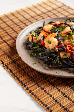 Black pasta with roasted prawns. Served on a plate. Stone background. Chopsticks or fork.の写真素材