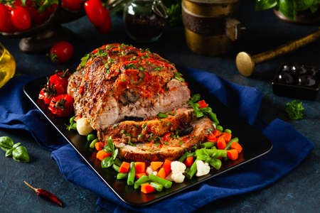 Whole roasted, stuffed with tomatoes and olives, pork neck. Dark background, dark mood.の写真素材