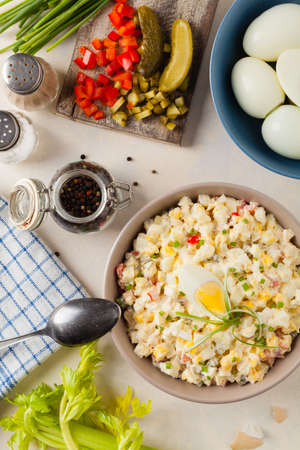 A light egg salad with celery, gherkin, pepper and mayonnaise. Served in a bowl on a light background. Top view.の写真素材