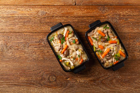 Traditional chicken stew with mushrooms and vegetables. Chicken casserole. Served in black pots.の写真素材