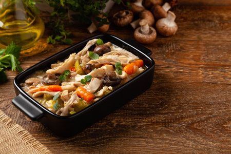 Traditional chicken stew with mushrooms and vegetables. Chicken casserole. Served in black pots.の写真素材