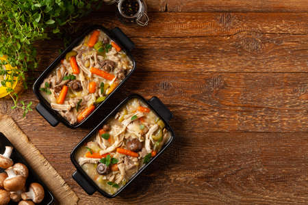 Traditional chicken stew with mushrooms and vegetables. Chicken casserole. Served in black pots.の写真素材