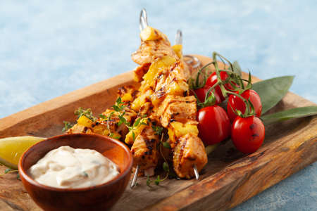 Grilled shashlik with salmon and pineapple. Served with yoghurt sauce. Blue painted background.の写真素材