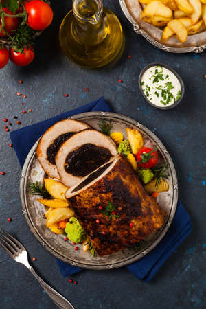 Whole roasted pork loin stuffed with dried plum. Top view. Dark blue background.の写真素材