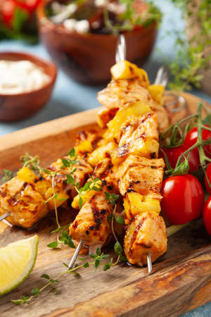 Grilled shashlik with salmon and pineapple. Served with yoghurt sauce. Blue painted background.の写真素材