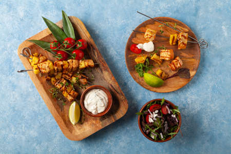 Grilled shashlik with salmon and pineapple. Served with yoghurt sauce. Blue painted background.の写真素材