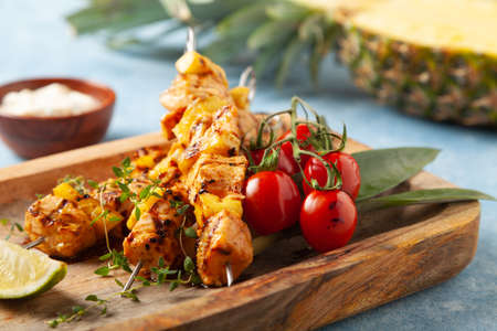 Grilled shashlik with salmon and pineapple. Served with yoghurt sauce. Blue painted background.の写真素材