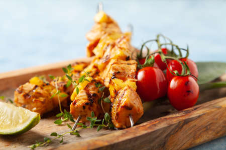 Grilled shashlik with salmon and pineapple. Served with yoghurt sauce. Blue painted background.の写真素材
