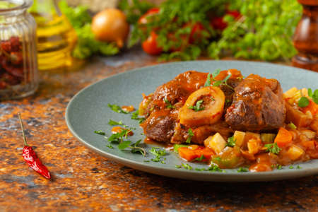 Ossobuco served with stewed vegetables. Colorful background. Gray plate.の写真素材