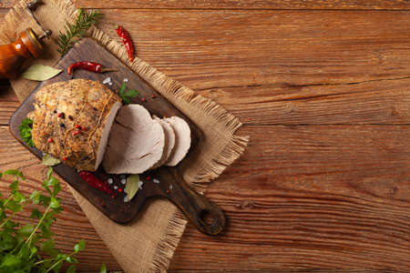 Crispy, cooked ham. Served with spices on a wooden board. Top view.の写真素材