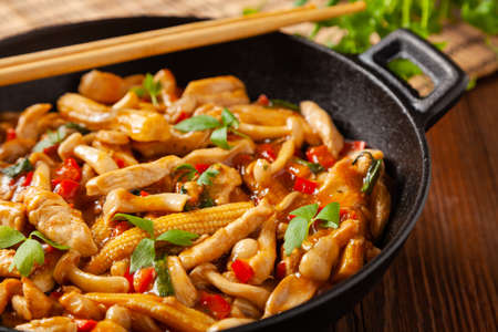 Traditional noodles with shimeji mushrooms and chicken. Prepared in a wok. Wooden background.の写真素材