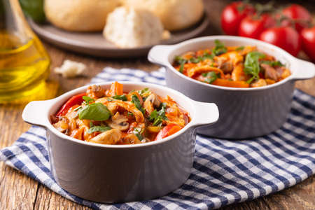 Chicken stew with peppers, mushrooms and tomatoes. Wooden background.の写真素材