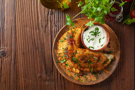 Traditional cheebureki, served on a wooden plate with sauce. Decorated with parsley.の写真素材