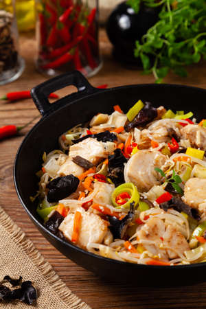 Chinese style cod, prepared in a wok. Natural wooden background.の写真素材