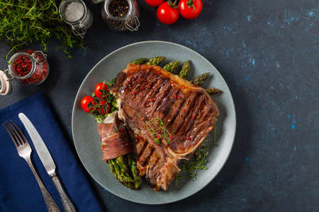 Grilled, medium-baked t-bone beef steak. Served with asparagus.の写真素材