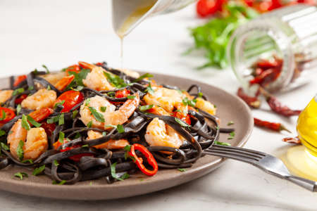 Black pasta with roasted prawns. Served on a plate. Stone background. Chopsticks or fork.の写真素材