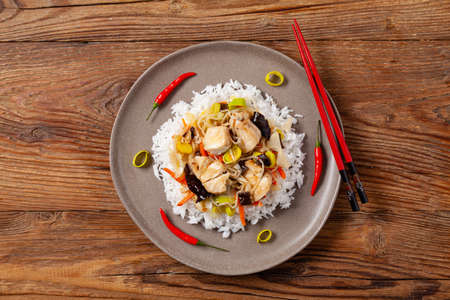 Chinese style cod, served on a plate with white rice. Natural wooden background.の写真素材
